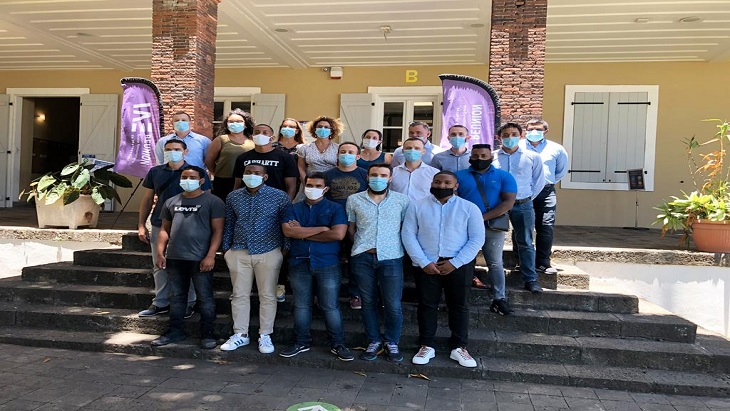 Group of students from the first class of the DistriSup training program and GBH employee on the steps in front of a building